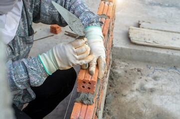 masonry worker make concrete wall by cement block and plaster at construction site