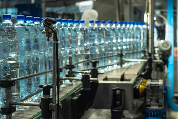 Blue plastic mineral water bottles on a conveyor line. Food production.