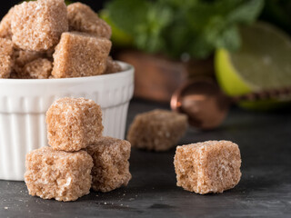 Brown cane sugar cubes lie on the table with mint and lime. Copy space.