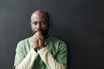 Portrait of African pensive man looking at camera standing against the black background