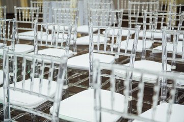 Glass chairs stand in a row in a beautiful wedding outing ceremony