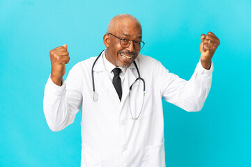 Senior doctor man isolated on blue background celebrating a victory