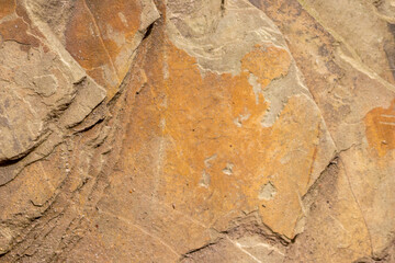 Raw rock in orange with minerals and metals as natural stones background with crushed and rough material at a rough coast or rocky beach show stone quarry and sandstones in broken surface granite form