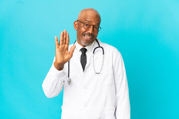 Senior doctor man isolated on blue background saluting with hand with happy expression