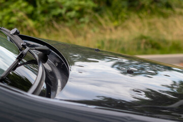 Bumped car engine hood after heavy storm as extreme weather and fallen trees and hail damage shows...
