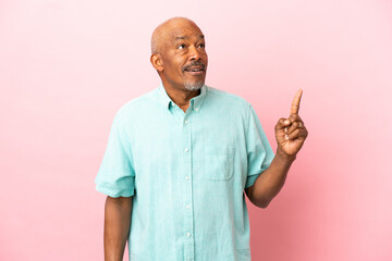 Cuban senior isolated on pink background thinking an idea pointing the finger up