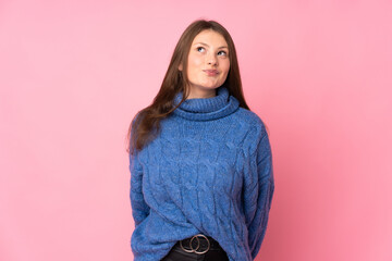 Teenager caucasian girl isolated on pink background and looking up