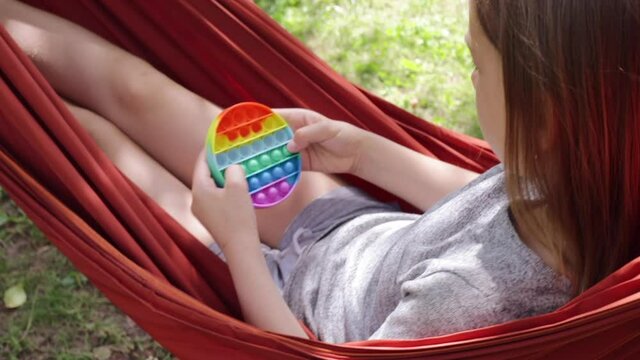 Сhild plays push pop bubble fidget toy outdoors