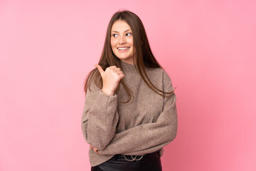 Teenager caucasian girl isolated on pink background pointing to the side to present a product