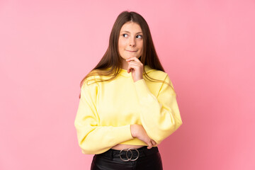 Teenager caucasian girl isolated on pink background having doubts and thinking