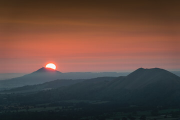 Sun rising behind the hill in Shropshire Hills, UK