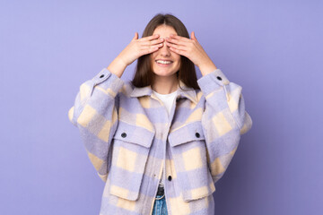 Teenager caucasian girl isolated on purple background covering eyes by hands and smiling