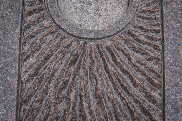 abstract structure of carved granite stone, fragment of a monument, concentric lines, water on artwork after rain	