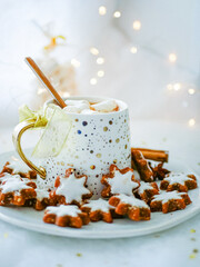 Christmas hot cocoa with marshmallows in a festive cup on a white plate with asterisk cookies. Christmas drink blur background copy space