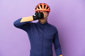 Young Brazilian cyclist man isolated on purple background covering eyes by hands. Do not want to see something