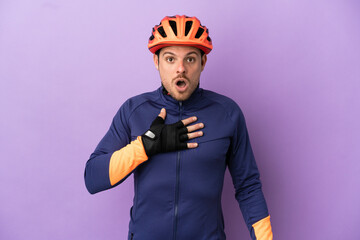 Young Brazilian cyclist man isolated on purple background surprised and shocked while looking right - obrazy, fototapety, plakaty