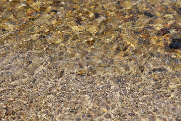 Clear water flowing through the pebbles in the creek