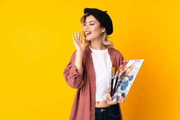 Young artist girl holding a palette isolated on yellow background shouting with mouth wide open