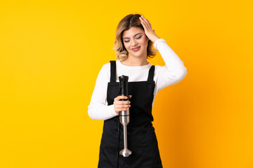 Girl using hand blender isolated on yellow background laughing