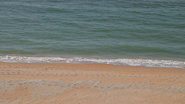 Sea surf, waves on waters, beach with yellow sand on coast.