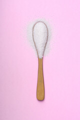 Wooden spoon with sweetener on pink background