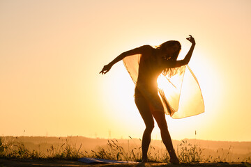 Silhouette of dancing young woman in sunrise