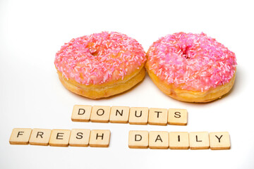 Two Iced Ring Donuts On A White Background With A Sign Reading Donuts Fresh Daily