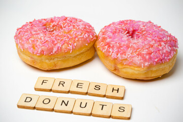Two Iced Ring Donuts On A White Background With A Sign Reading Fresh Donuts