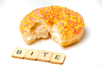 An Iced Ring Donut On A White Background With A Bite Taken Out and A Sign Reading Bite