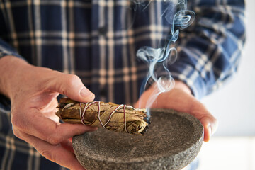 Mann räuchert mit einem Smudge Stick Kräuterbündel Weißer Salbei, Yerba Santa  das Haus -...