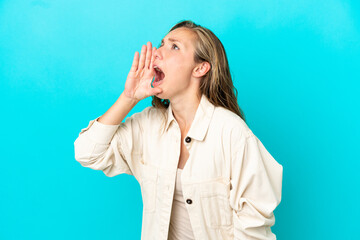 Young caucasian woman isolated on blue background shouting with mouth wide open to the side