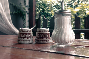 Wooden table with salt shaker, pepper shaker and sugar bowl. The Ukrainian inscriptions read "salt and pepper"