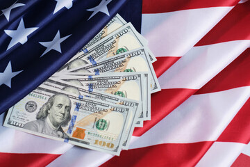 Hundred dollar bills are laid out on flag of United States of America.