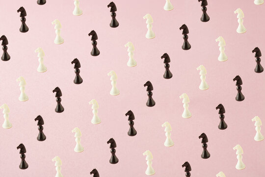 Chess pattern of black and white horses on pink background. Minimal lay out.