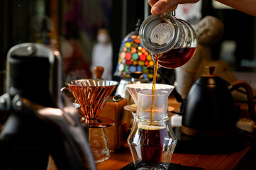 The barista is making coffee in a drip method for customers.