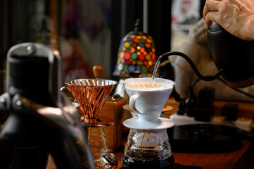 The barista is making coffee in a drip method for customers.