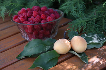 Raspberries and apricots in the summer kitchen. Red berries in a transparent crystal bowl. New harvest