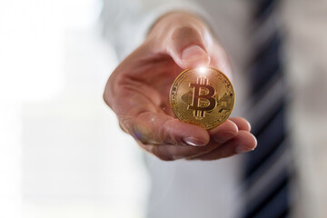 A businessman in a suit is holding a Bitcoin, Cryptocurrency