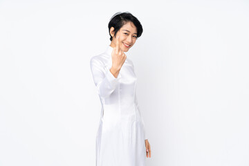 Young Vietnamese woman with short hair wearing a traditional dress over isolated white background doing coming gesture