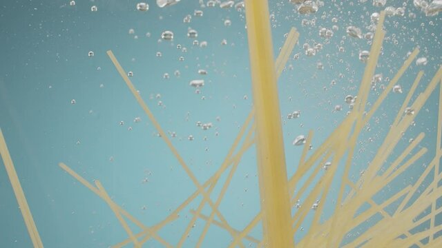 Spaghetti throwing into the water on blue background Pasta falling into water