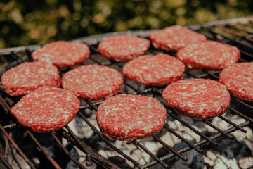Barbecue grill with fresh natural burgers ready for cooking on the fire
