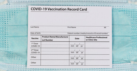 Covid 19 vaccination record with facemask in background