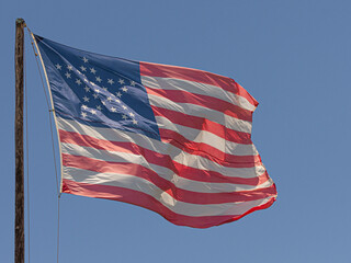 Close up of a vintage American flag with 38 stars in the shape of a star flying in the breeze on a...
