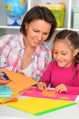 Fototapeta premium mother and daughter gluing and cutting paper