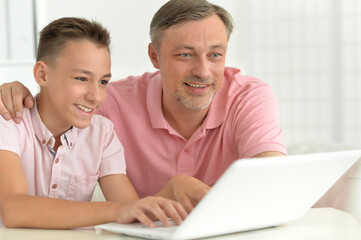 son and father using laptop at home