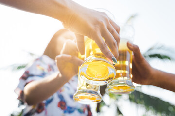 Cropped shot of people holding beer glasses celebrating in the summer camping party outdoor....