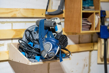  selected focus close up of a blue respirator hanging off an electric power tool plunge saw sitting...