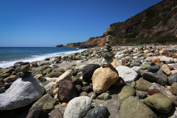 Fototapeta na wymiar Spiaggia con grandi sassi e pila di ciottoli in equilibrio in primo piano