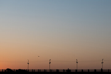 Obraz premium Minimal Shot of people walking on elevated wooden walkway at sunrise