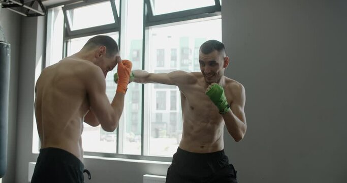 Two kickboxers are practising their strikes and punches in slow motion in the gym, mixed martial arts fighters are training, 4k 120fps Prores HQ